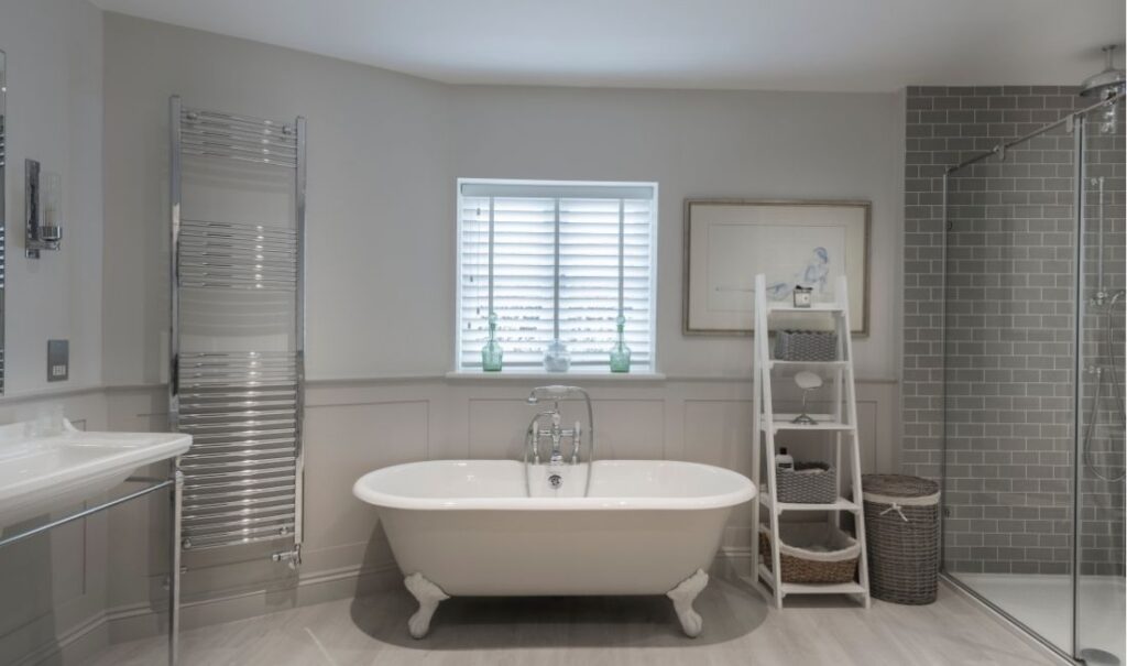 Venetian blind in stylish contemporary bathroom with freestanding roll top bath